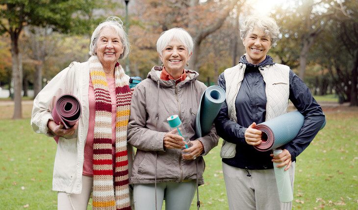 Three older women in a park with exercise mats