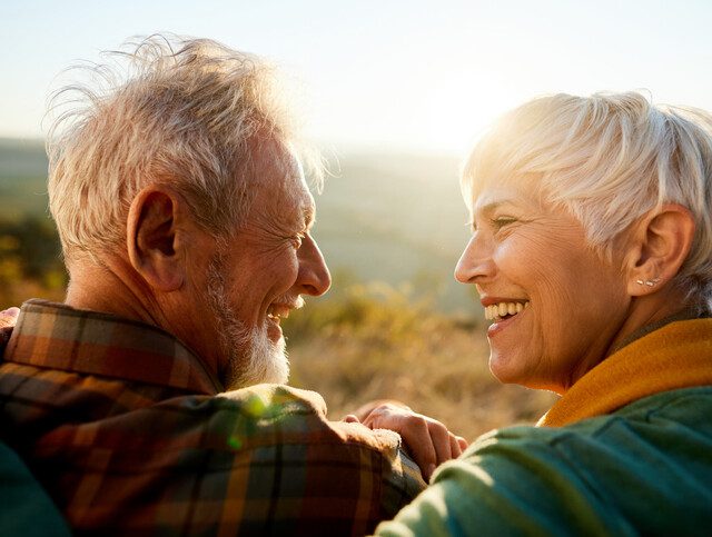 man and woman sitting outside smiling and looking at each other