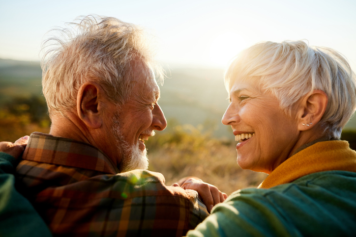 man and woman sitting outside smiling and looking at each other