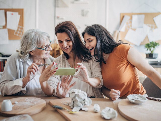 three generations of women working together on pottery and taking photos with their phone