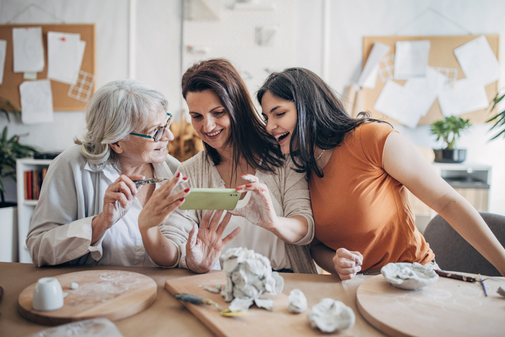 three generations of women working together on pottery and taking photos with their phone